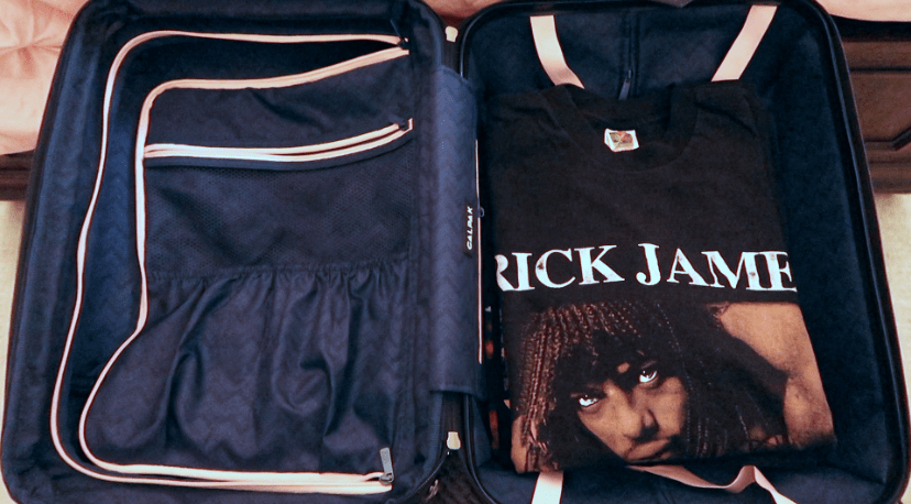 a suitcase laying open with a rick james tee on top