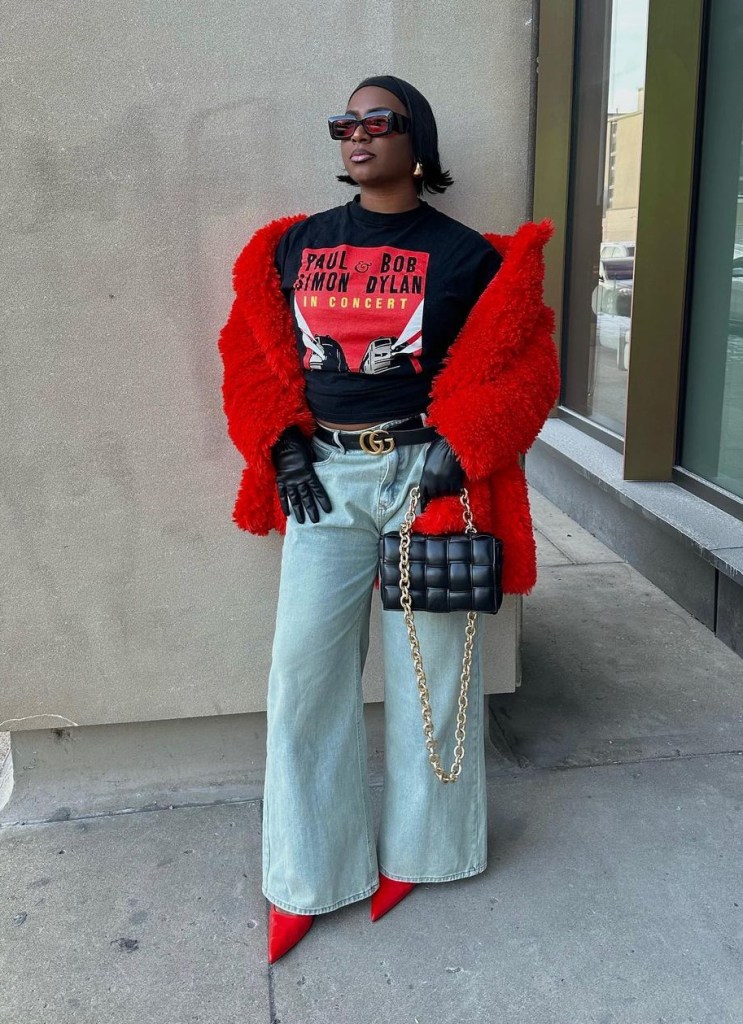 Cydney Paige in a black graphic tee, red faux fur, denim pants, and red pumps.